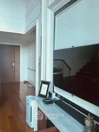 Spacious modern living room with wooden flooring and large TV setup