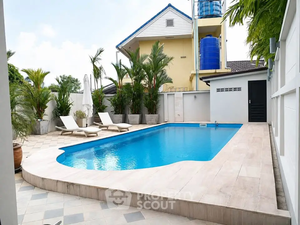 Luxurious outdoor pool area with sun loungers and lush greenery, perfect for relaxation and entertainment.