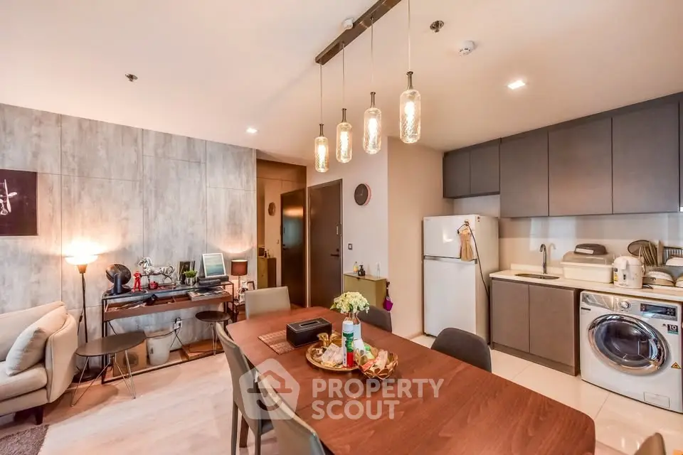 Modern open-plan living room with stylish kitchen and dining area, featuring contemporary lighting and appliances.