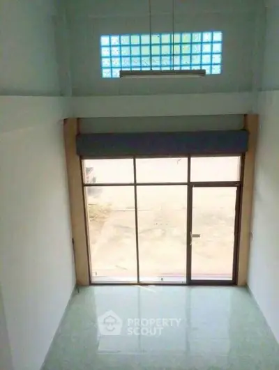 Spacious high-ceiling room with large window and modern design