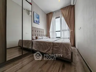 Modern bedroom with mirrored wardrobe and large window view.