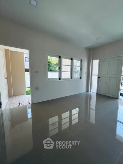 Spacious empty room with glossy tiled floor and large windows, perfect for customization.
