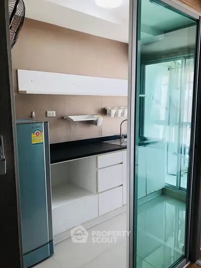 Modern kitchen with sleek design and sliding glass door, featuring ample storage and natural light.