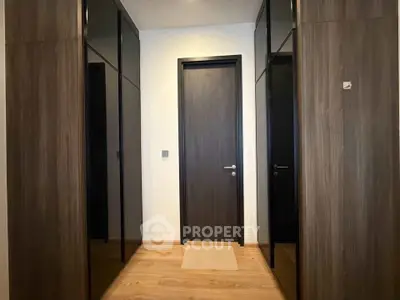 Modern hallway with sleek wooden doors and mirrored closets in a contemporary apartment.