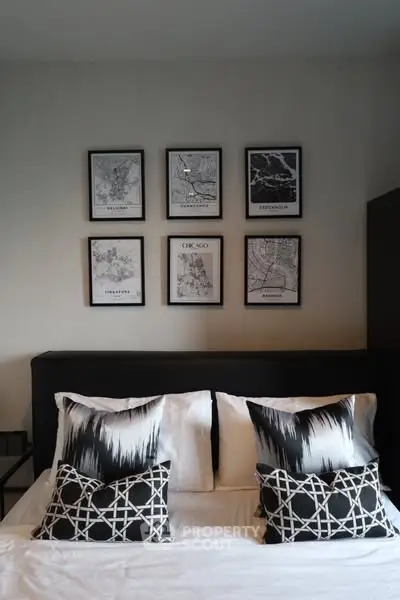 Modern bedroom with stylish decor and framed city maps above bed.