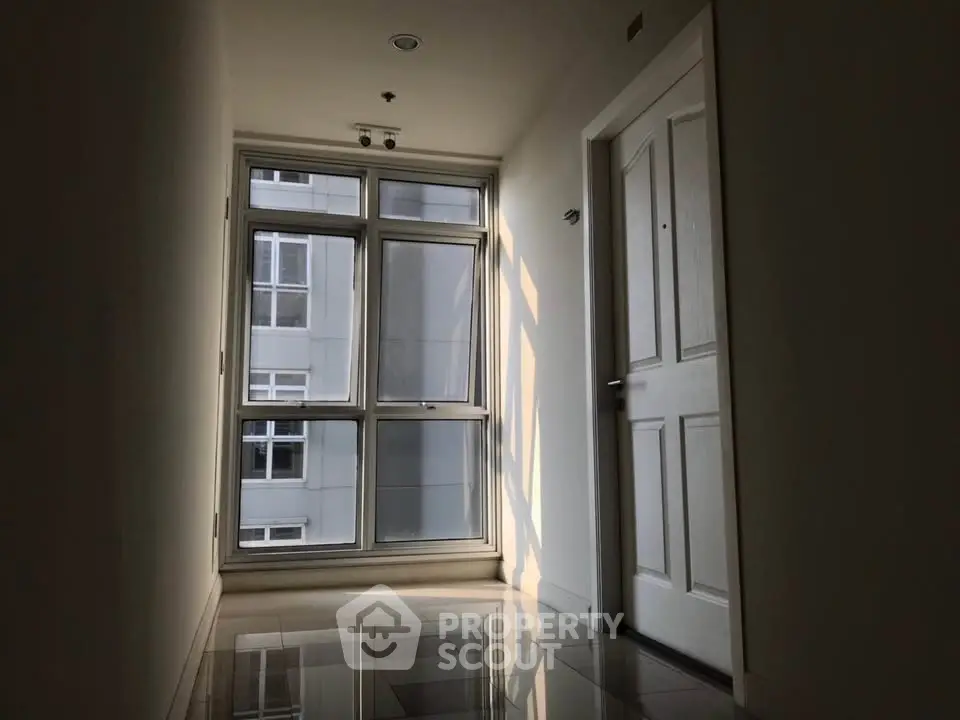 Bright corridor with large window and modern door in a contemporary building.
