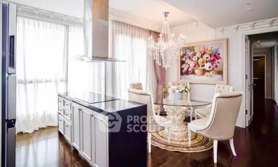 Luxurious dining area with elegant chandelier and modern kitchen island in upscale apartment.