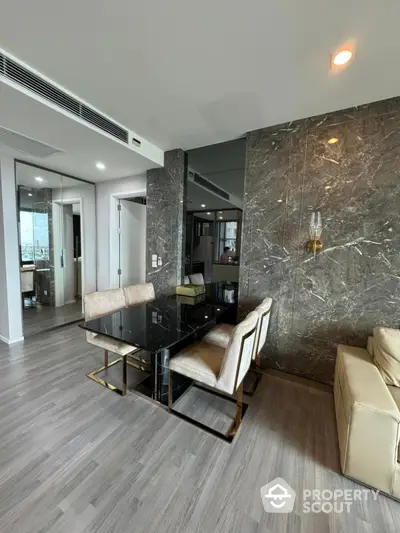 Modern dining area with marble accent wall and sleek glass table in luxury apartment