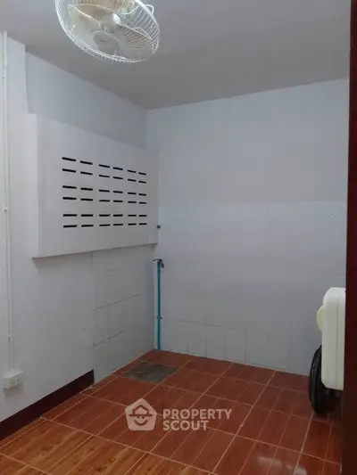Compact utility room with tiled floor and ceiling fan, ideal for storage or laundry setup.