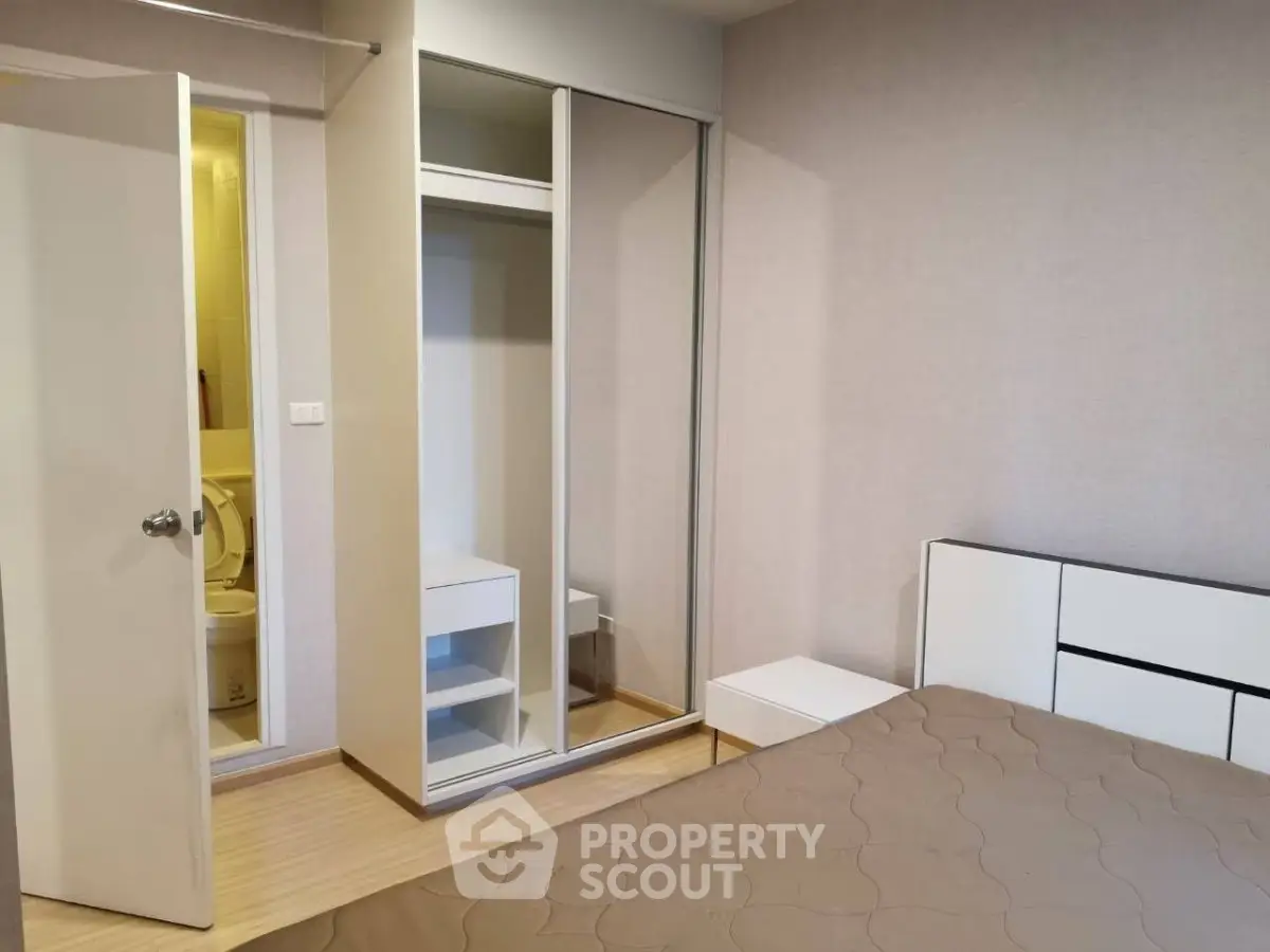 Modern bedroom with built-in wardrobe and en-suite bathroom in stylish apartment.