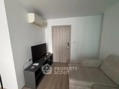 Modern living room with sleek TV setup and cozy sofa, featuring minimalist design and air conditioning.