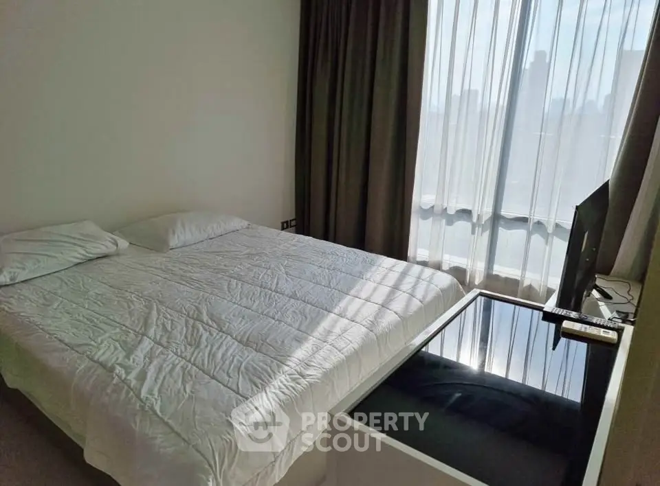 Cozy bedroom with large window offering city views, featuring a comfortable bed and modern decor.