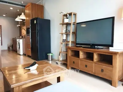 Modern living room with wooden furniture and large TV, open kitchen layout, and stylish decor.