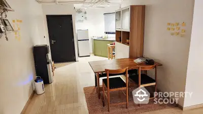 Modern dining area with wooden table and chairs, adjacent to a compact kitchen in an open layout.