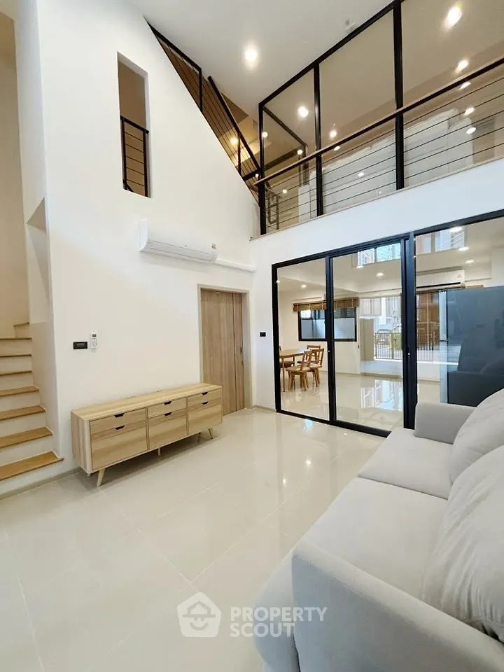 Spacious modern living room with high ceilings and elegant glass railing