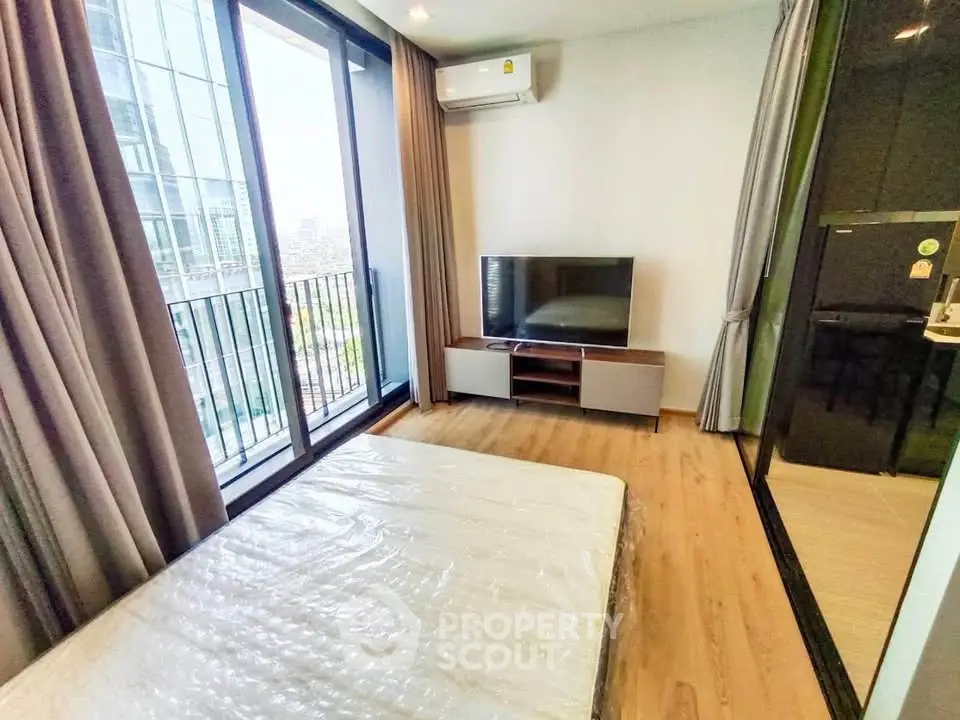 Modern bedroom with balcony view, featuring a sleek TV setup and air conditioning.