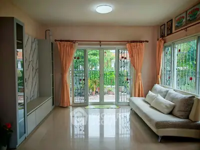Spacious living room with elegant decor and garden view, featuring large windows and comfortable seating.