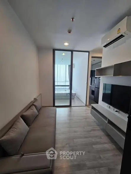Modern living room with sleek design and air conditioning, featuring a cozy sofa and TV unit.