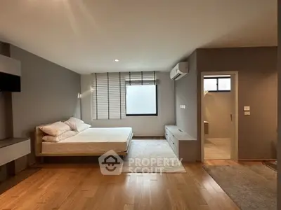 Spacious modern bedroom with wooden flooring and natural light.