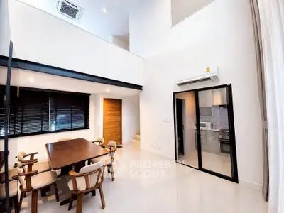 Spacious modern dining area with high ceiling and open kitchen layout