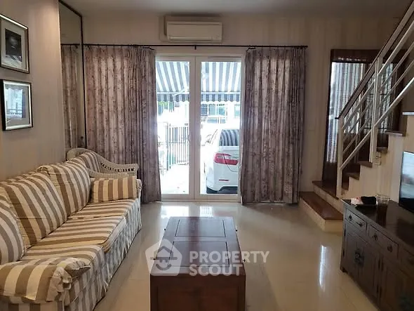 Cozy living room with striped sofa and modern staircase, perfect for relaxation.