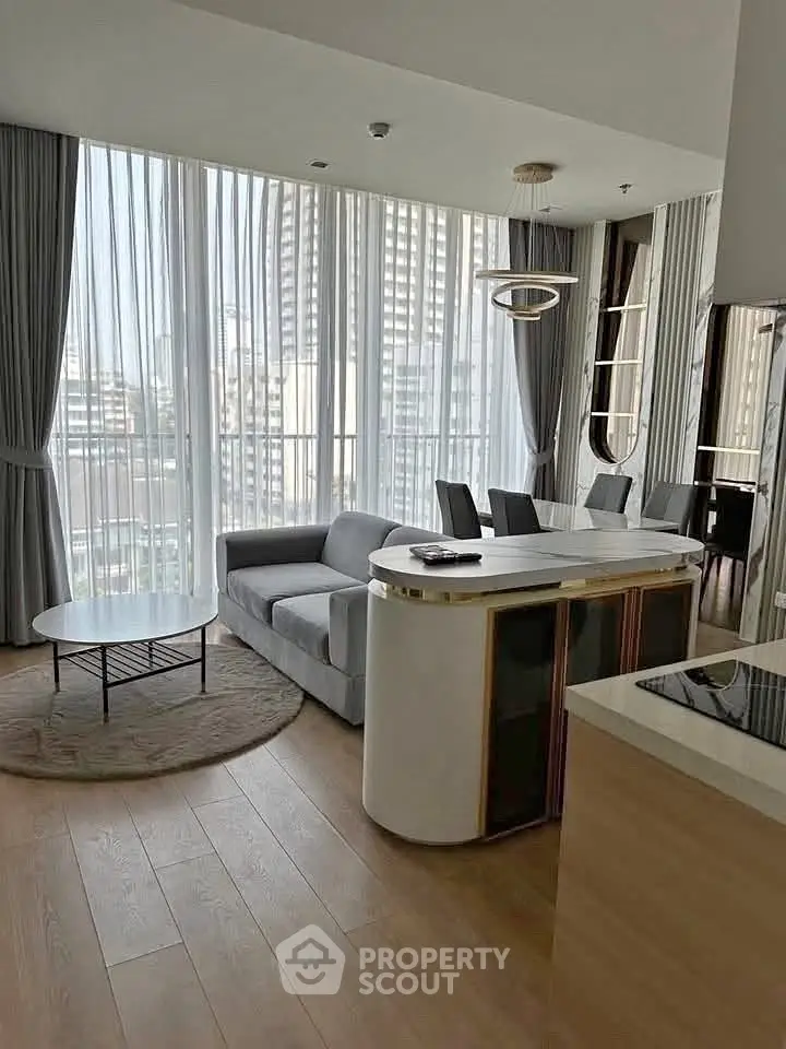 Modern living room with floor-to-ceiling windows and city view, featuring sleek furniture and elegant decor.