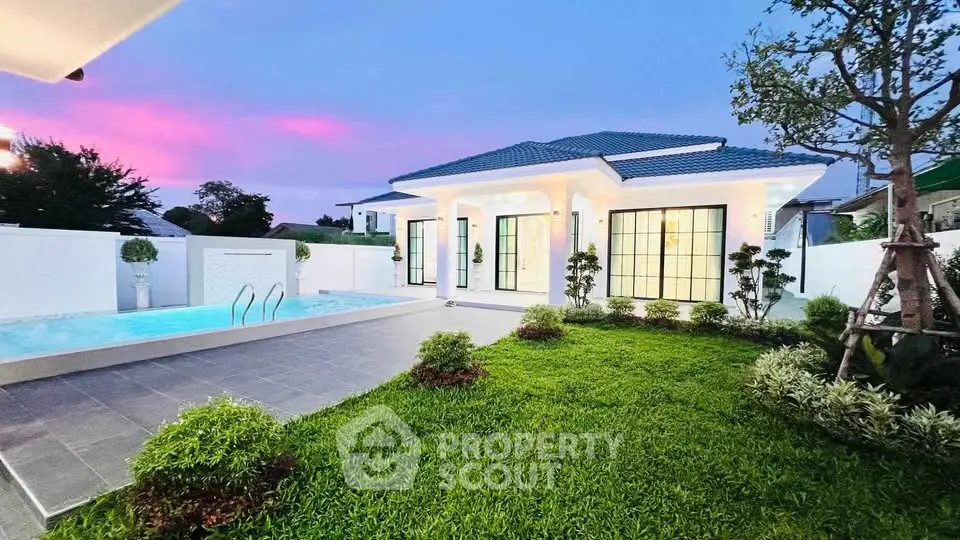 Stunning modern villa with pool and lush garden at sunset, perfect for luxury living.
