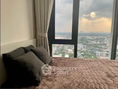Luxurious bedroom with stunning city view from high-rise window, featuring plush bedding and elegant curtains.
