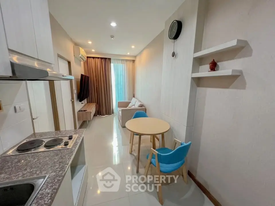 Modern apartment interior with compact kitchen and cozy living area, featuring stylish furniture and decor.