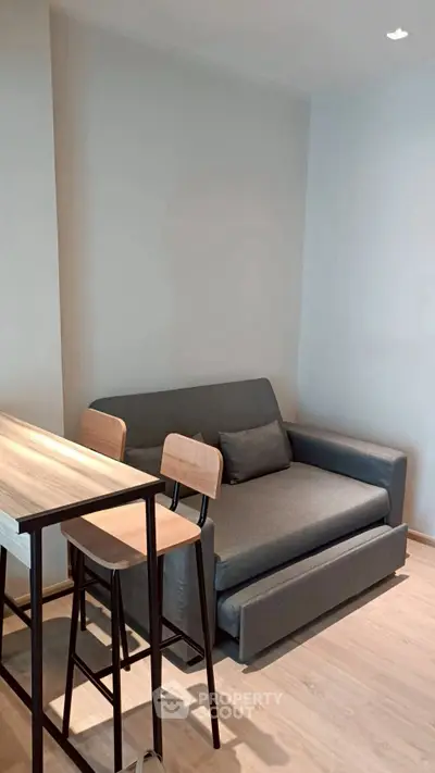 Modern living room with sleek gray sofa and stylish wooden bar stools