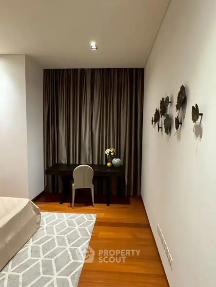 Elegant bedroom with study area featuring modern decor and wooden flooring.