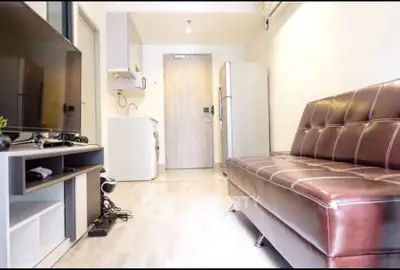 Modern living room with leather sofa, flat-screen TV, and sleek appliances in a stylish apartment.