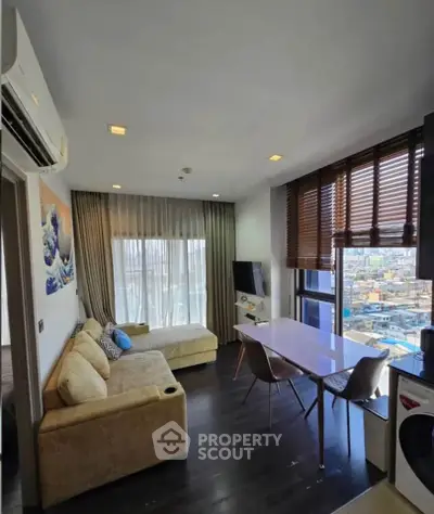 Modern living room with city view, featuring stylish furniture and large windows for natural light.