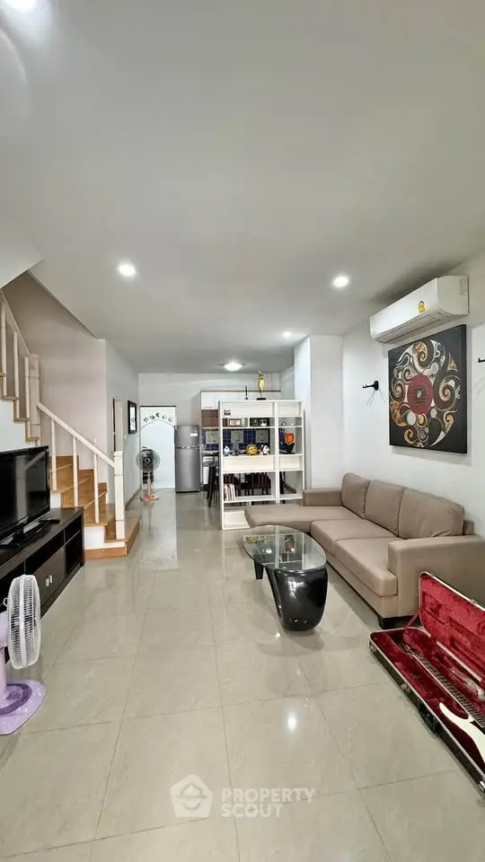 Spacious modern living room with elegant decor and open layout, featuring a cozy sofa and stylish staircase.