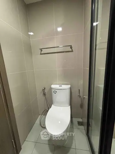 Modern bathroom with sleek toilet and glass shower enclosure in a contemporary apartment.