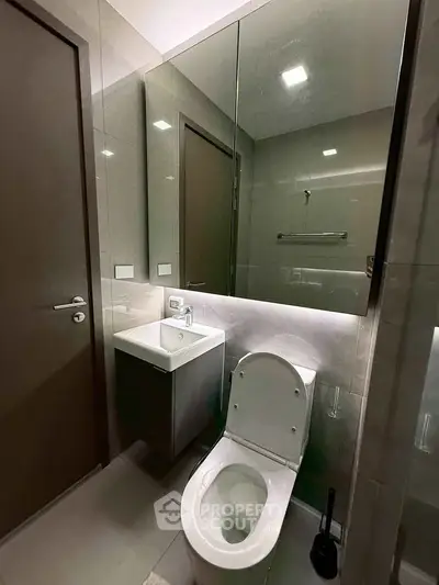 Modern bathroom with sleek fixtures and mirrored cabinet in a contemporary apartment.