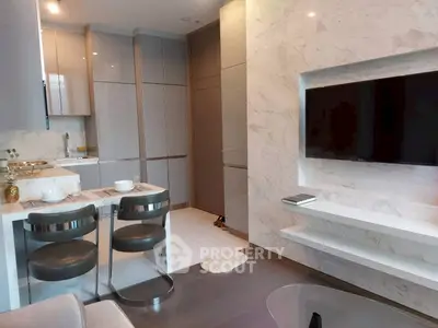 Modern living room with sleek kitchen, marble accents, and wall-mounted TV in luxury apartment.