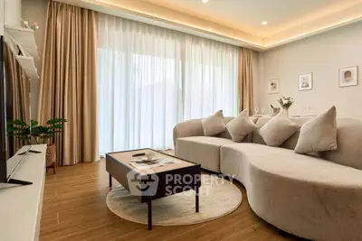 Luxurious modern living room with elegant curved sofa and floor-to-ceiling windows.