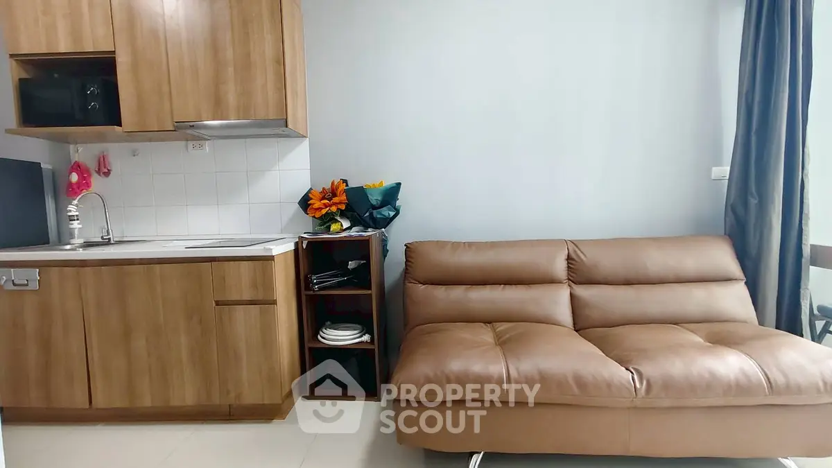 Modern compact living room with kitchenette and stylish brown sofa