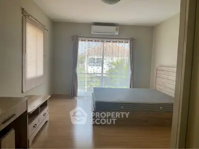 Spacious bedroom with large window and wooden flooring in modern home