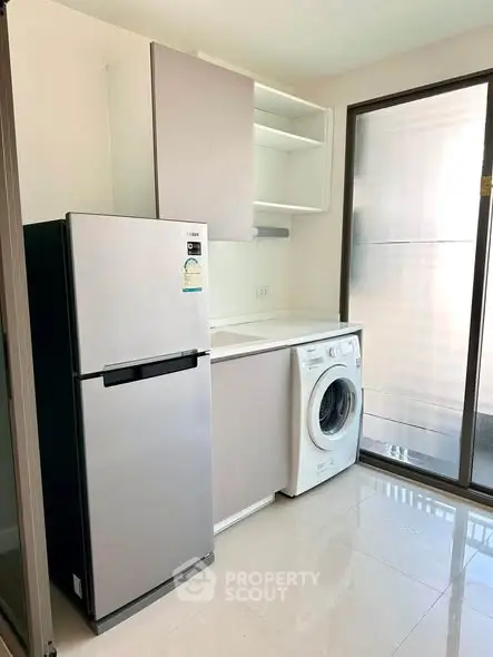 Modern kitchen with fridge and washing machine in sleek apartment