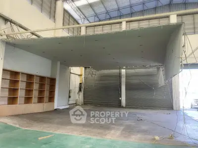 Spacious industrial warehouse interior with high ceilings and shelving units.