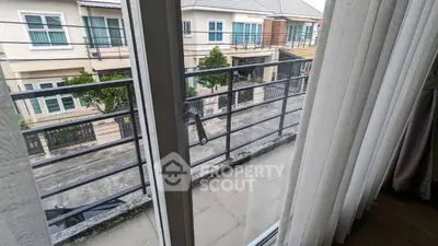 Charming balcony view from modern apartment overlooking residential street.