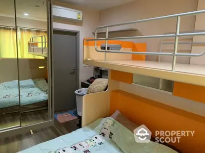 Compact and modern bedroom with bright orange bunk beds, mirrored wardrobe, and wood flooring, ideal for maximizing small living spaces.