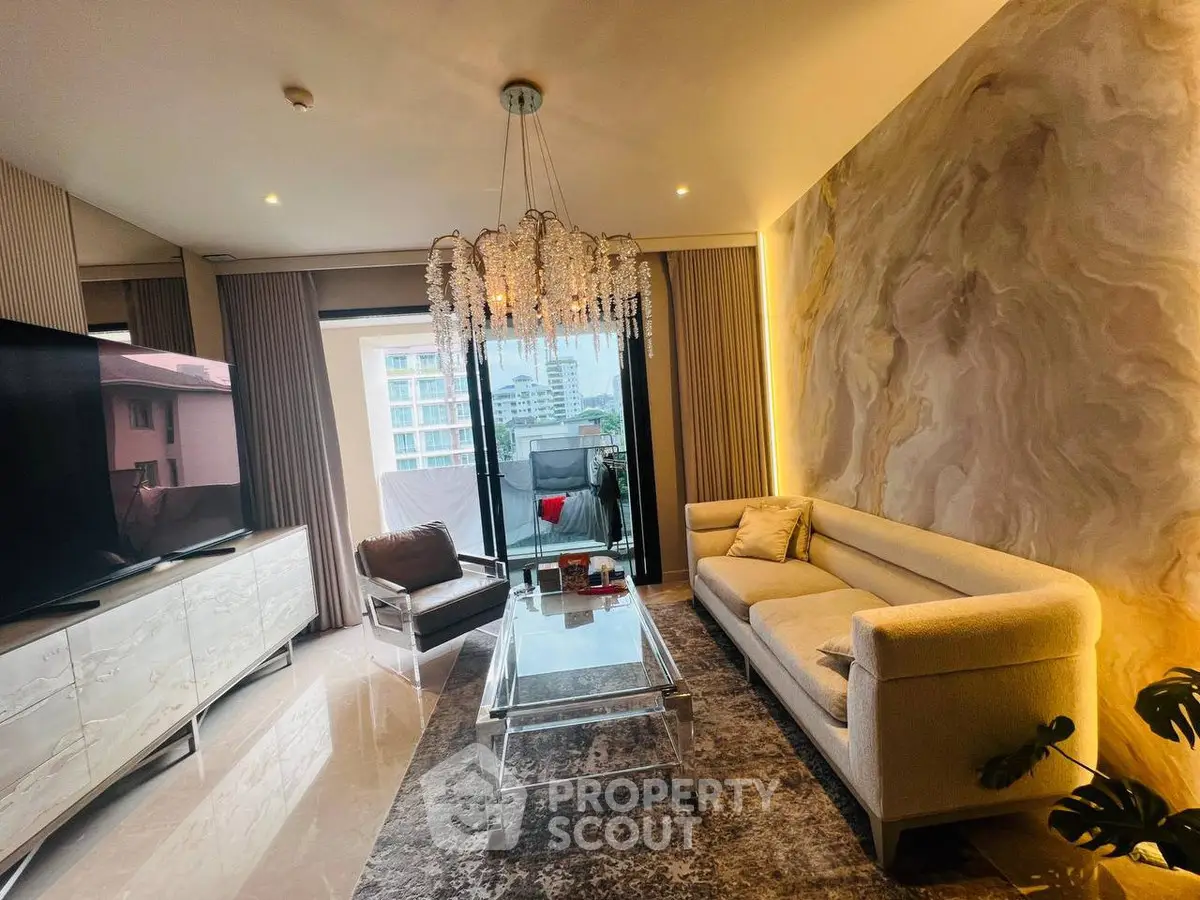 Luxurious living room with elegant chandelier and stunning city view from balcony.