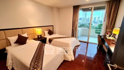 Spacious bedroom with twin beds and city view balcony in modern apartment