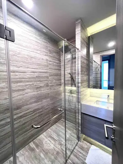 Luxurious modern bathroom with sleek glass shower and elegant marble tiles.