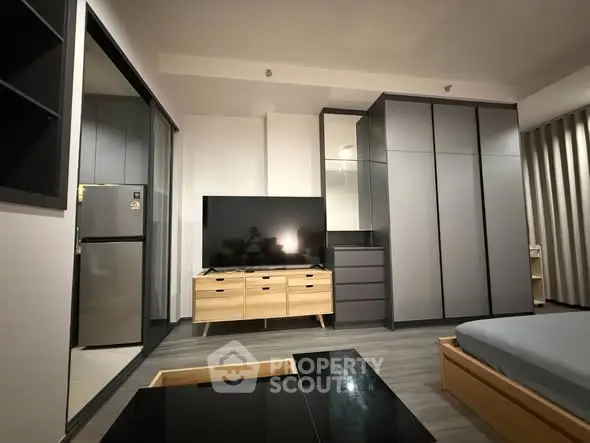 Modern bedroom with sleek furniture and large TV, perfect for urban living.
