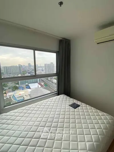 Cozy bedroom with city view, featuring a large window and air conditioning unit.