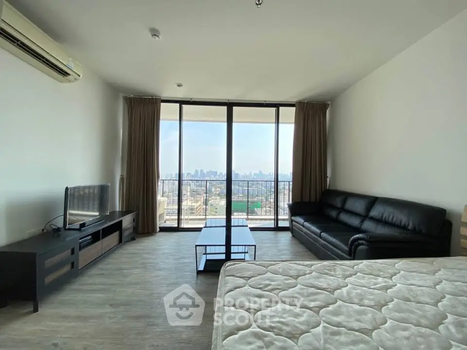 Spacious living room with city view, modern furniture, and large windows in a high-rise apartment.